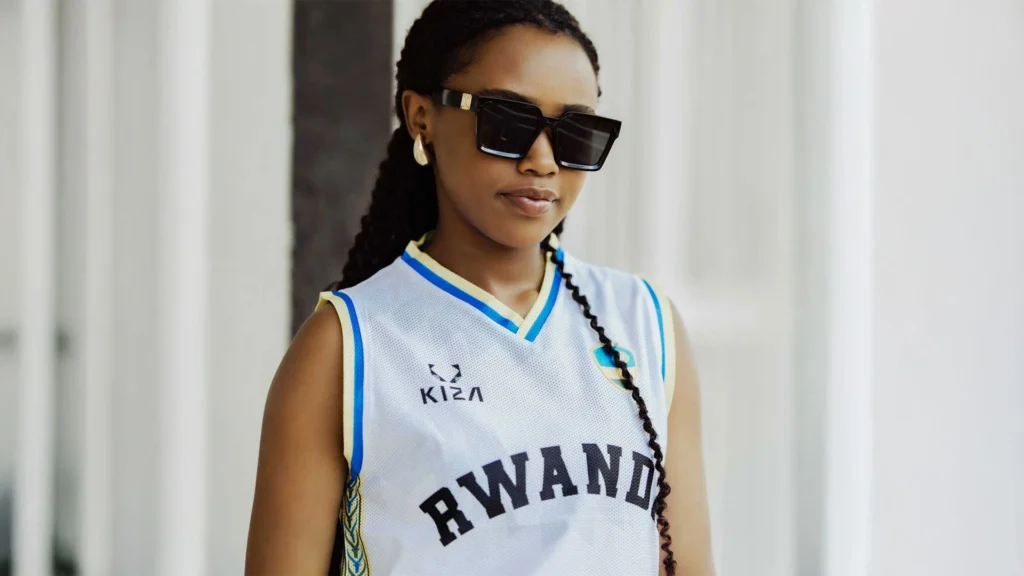 kiza-rwanda-basketball-jersey-fashion-pride Young woman wearing a KIZA Rwanda basketball jersey, blending fashion, national pride, and modern African identity